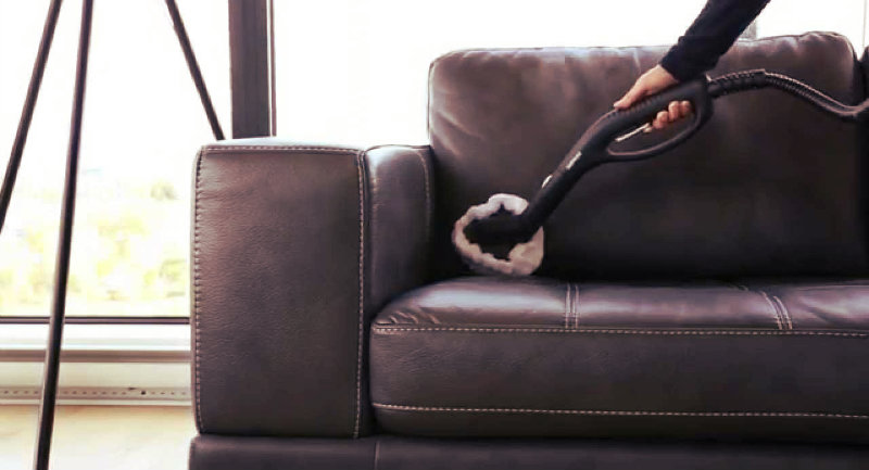 cropped image of a woman vacuuming a leather couch