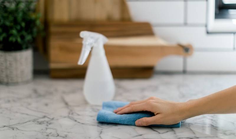 Hand of a woman scrubbing marble floor with a scrubber