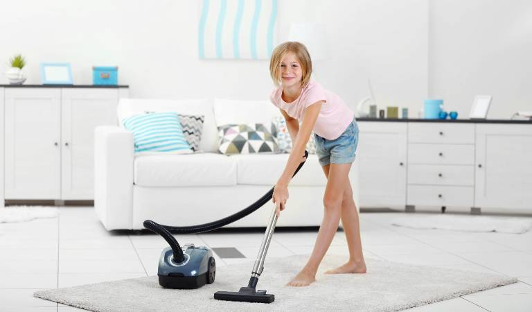 A child is vacuuming carpet inside a room
