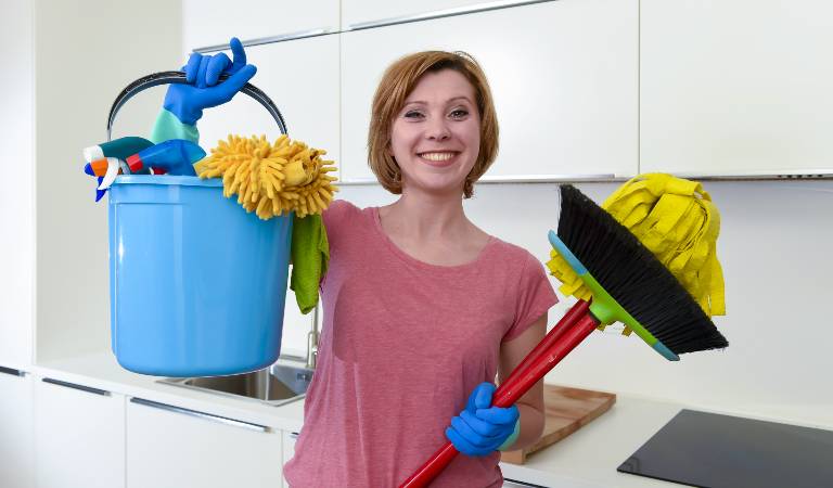 Woman holding a blue basket and a stick in her hand.