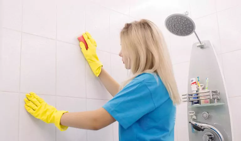 young woman cleaning tiles inside of a bathroom