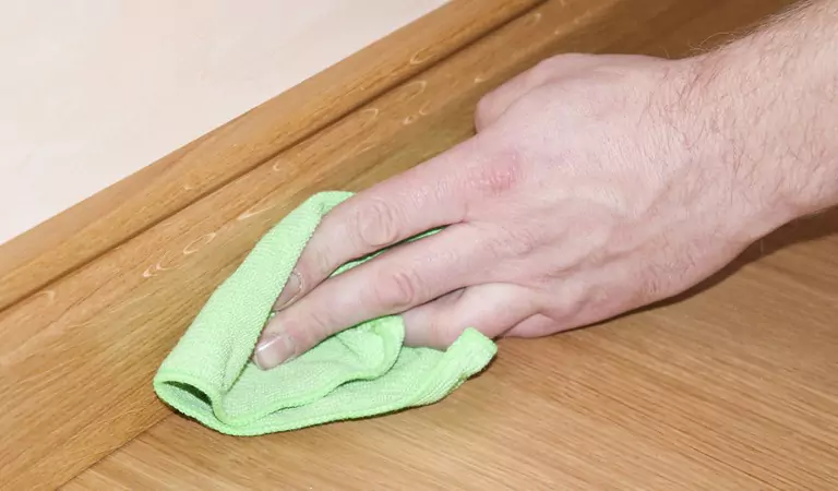 cropped picture of a person cleaning Skirting board