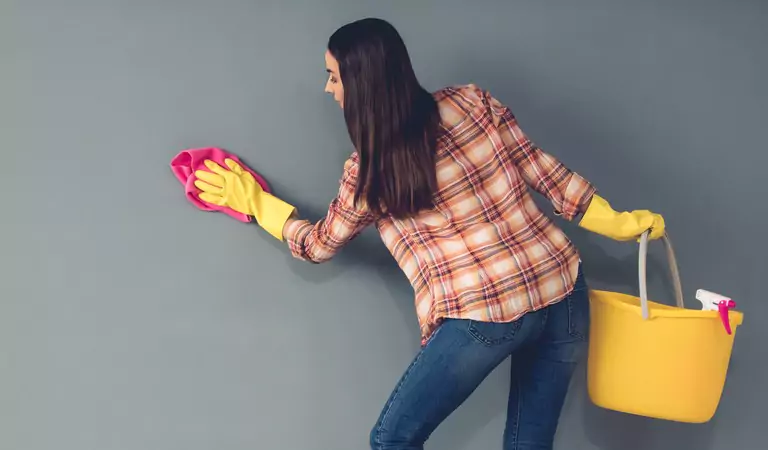 young woman wiping the walls inside of her house
