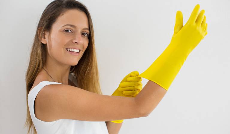 Woman in white top wearing yellow gloves