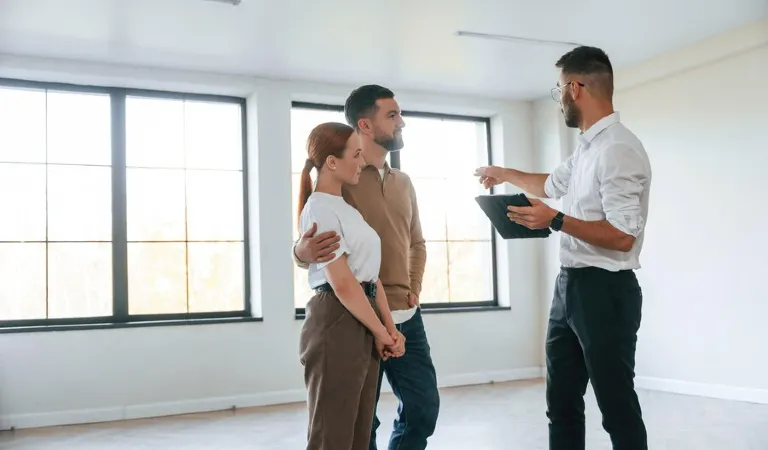 Landlord is talking with a couple and pointing somewhere in a house.