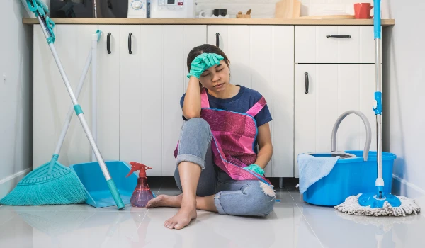 Tired young woman sitting on kitchen floor