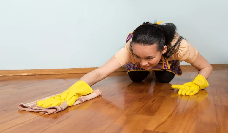 Young housewife with yellow gloves cleaning the floor