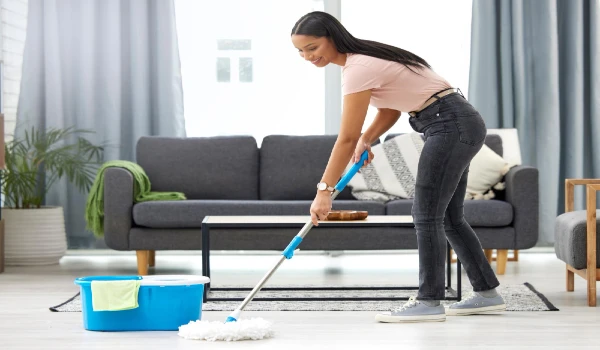 young woman mopping the floor while cleaning her home
