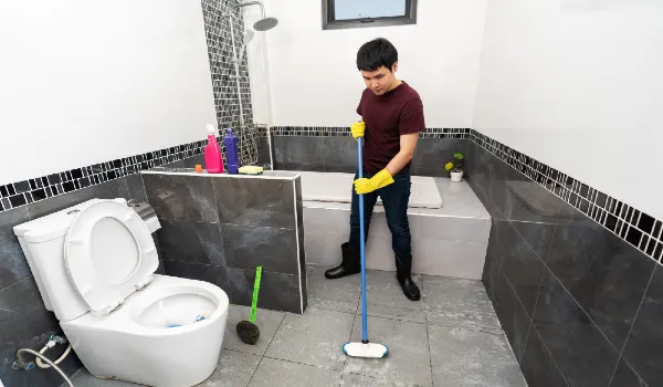 Young man using brush to cleaning the tile in the bathroom
