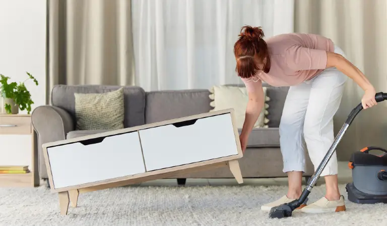 Woman vacuum and dust or dirt removal at home female cleaner lifting table and vacuuming for clean rug mat or floor in the lounge