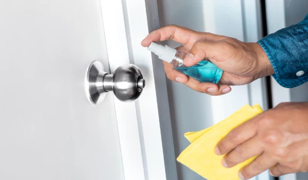 A person cleaning disinfecting the door knob
